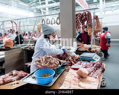 Eine kasachische Frau, die aus Pferdefleisch und Innerem Qazy, Pferdewurst, zubereitet. Fleischmarkt in Altyn Orda, Almaty, Kasachstan Stockfoto