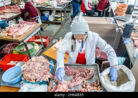 Eine kasachische Frau, die salzigen Knoblauch auf Pferdefleisch legt, um Qazy, Pferdewurst zuzubereiten. Fleischmarkt in Altyn Orda, Almaty, Kasachstan Stockfoto