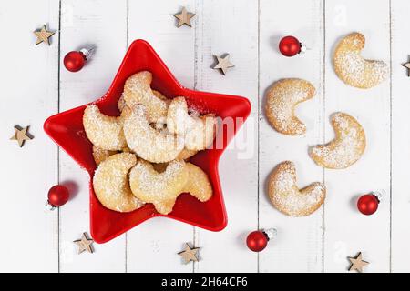 Draufsicht auf halbmondförmige Weihnachtsplätzchen namens 'Vanillekipferl', ein traditionelles österreichisches oder deutsches Weihnachtsplätzchen mit Nüssen und Puderzucker in einer Schüssel Stockfoto