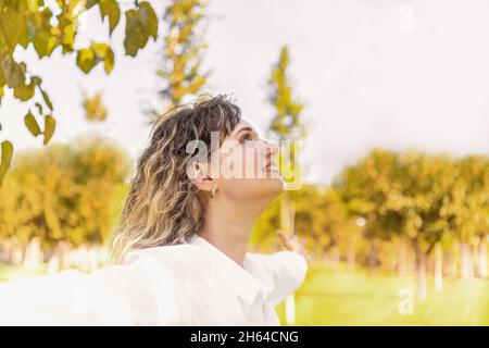 Profil einer blonden Frau, die die Arme im Freien hebt Stockfoto