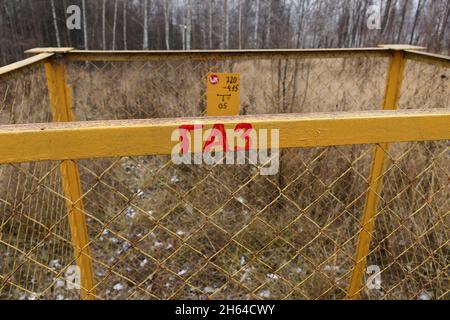 Gelbe Betonsäule mit Warnschild Gas, im Freien im Gras. Gasleitungen, Ventile und Geräte für eine Gaspumpstation Gasverteilergebäude Stockfoto