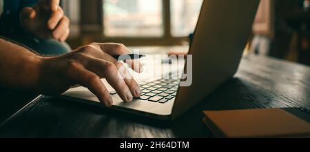 Nahaufnahme der männlichen Hände mit Laptop. Der Mann arbeitet von zu Hause aus. Freiberufler bei der Arbeit Stockfoto