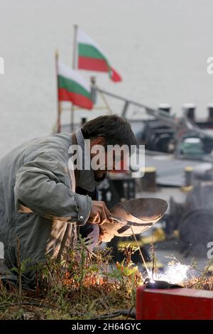 Ein Schweißer schweißt und repariert Maschinenteile im Freien. Stockfoto