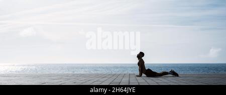 Fit junger Mann Stretching nach dem Training im Freien. Männlicher Athlet, der morgens während des Lockdown vor dem Fitnessstudio Fitnesstraining macht. Stockfoto