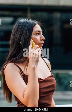 Vertikales Porträt einer schönen chinesin, die auf der Straße telefoniert Stockfoto