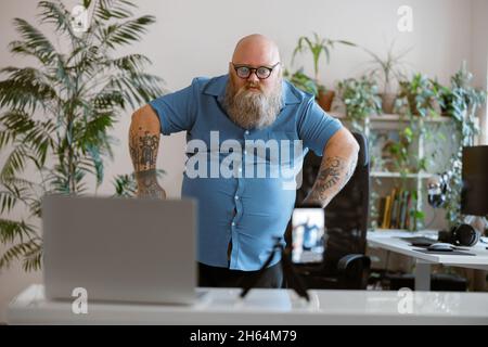 Verspielt plump Mann in blauem Hemd schießt neue Video für Blog mit Handy zu Hause Stockfoto