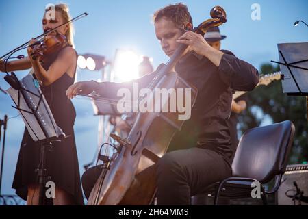Ein Violoncellist spielt im Orchester bei einem Konzert im Freien Stockfoto