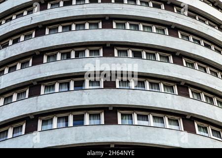 Die einheitlichen Fenster eines hohen zylindrischen grauen Hotelgebäudes - Stadtgebäude Hintergrund. Stockfoto