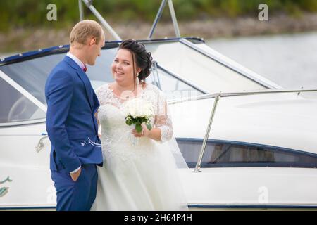 Die fette Braut und der fette Bräutigam stehen in der Nähe der Yacht und sprechen miteinander. Stockfoto