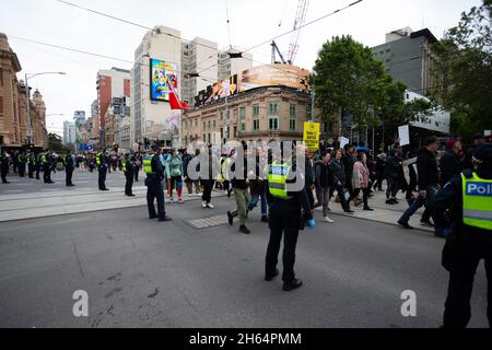 Melbourne, Australien. 13. November 2021. Die Polizei beobachtet, wie Demonstranten während eines Protestes gegen die Regierung von Andrew vor den Schritten des State Parliament in Melbourne entlang der Flinders Street marschieren. Tausende von Demonstranten mussten den Regen ertragen, um gegen die Impfstoffmandate sowie gegen das drakonische Pandemie-Gesetz der Regierung Andrews zu kämpfen. Kredit: Dave Hewison/Speed Media/Alamy Live Nachrichten Stockfoto