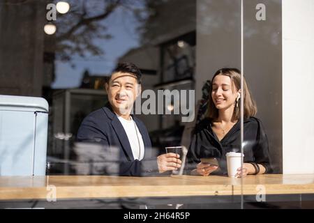 Multirassisches Paar trinkt Kaffee am Tisch im Café Stockfoto