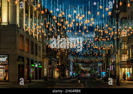 LONDON - 13. NOVEMBER 2021: Die Oxford Street in London ist dieses Jahr zu Weihnachten mit funkelnden Sternen geschmückt, die über die Länge der Straße drapiert sind. Stockfoto