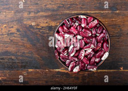 Rote und weiße Bohnen in einer Schüssel auf einem Holzhintergrund. Draufsicht. Stockfoto