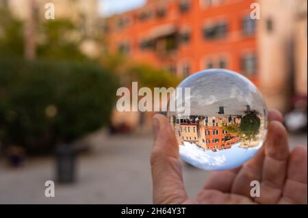 Hand hält Glaskugel vor bunten Häusern in Venedig (Italien) Stockfoto