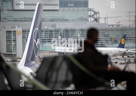 08. November 2021, Hessen, Frankfurt/Main: Das Lufthansa-Logo ist hinter einem wartenden Passagier am Frankfurter Flughafen zu sehen. Foto: Sebastian Gollnow/dpa Stockfoto