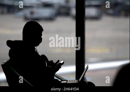 08. November 2021, Hessen, Frankfurt/Main: Ein Mann arbeitet mit Laptop und Smartphone im Wartebereich eines Tores am Frankfurter Flughafen. Foto: Sebastian Gollnow/dpa Stockfoto