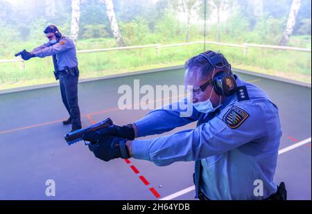 10. November 2021, Sachsen, Schneeberg: Zwei Polizisten trainieren auf dem neuen Weltraumschießplatz der Polizeitechnischen Schule. Am selben Tag wurde auf dem Gelände eine der modernsten Schießstrecken in Betrieb genommen. In der 6.6 Millionen Euro teuren Anlage können mit Hilfe von Beamern und einem Bildschirm Schießübungen in einem Winkel von 180 Grad durchgeführt werden. Ziel der Schulung ist es, jedem Polizisten und jeder Polizistin zu ermöglichen, den sicheren Umgang mit Waffen zu üben und zu verinnerlichen. Die Schule in Schneeberg bildet derzeit rund 650 Polizeianwärter aus und organisiert auch Fortbildungen. P Stockfoto