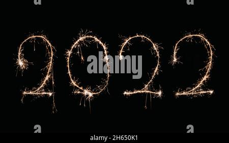 Die Nummer 2022 ist mit einem Wunderkerzen geschrieben. Jahr zweitausend zweiundzwanzig auf schwarzem Hintergrund. Stockfoto