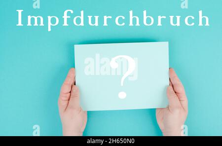 Die Worte Impfstoffdurchbruch stehen auf einem Papier, deutsche Sprache, Fragezeichen, Hände halten die Botschaft, covid-19-Impfung Stockfoto