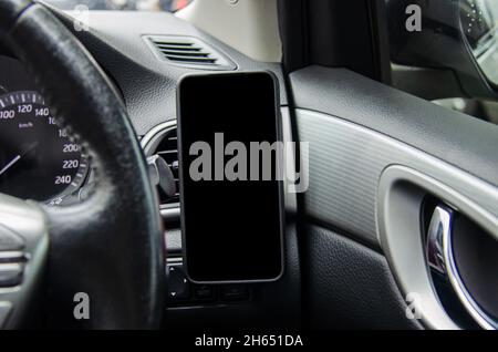 Handy auf dem Auto Luftauslass.Blank mit weißem Bildschirm.Mock up Smartphone im Auto. Stockfoto