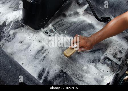 Waschen Sie den Teppich Auto.Detaillierung auf dem Innenraum des modernen Auto.Clean mit einer Bürste und Reinigungslösung auf dem Teppich Auto. Stockfoto