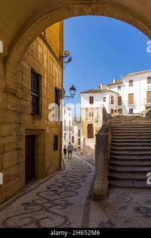 Fußgänger in der Calle Baja Iglesia, Alhama de Granada, Provinz Granada, Andalusien, Spanien. Die Stufen rechts führen hinauf zur Iglesia de la Encarna Stockfoto