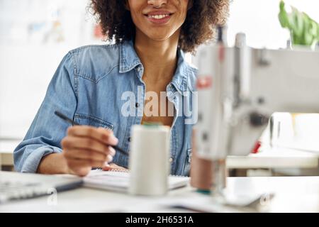 Die afroamerikanische Modedesignerin zeichnet am Arbeitsplatz in der Nahaufnahme des hellen Studios Models Stockfoto