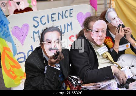 Aktivisten, die als Adani-Vorsitzender Gautam Adani, Science Museum Direktor Ian Blatchford und Shell-CEO Ben van Beurden gekleidet sind, liegen während der Demonstration auf einem Bett mit gefälschtem Geld, Kohle und gefälschtem Öl. Extinction Rebellion-Aktivisten veranstalteten einen Protest gegenüber dem Science Museum in South Kensington gegen das Sponsoring des Museums durch die fossilen Energiekonzerne Shell und Adani. Stockfoto