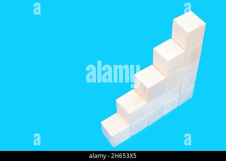 Treppen aus aufsteigenden Holzspielzeugblöcken auf blau isoliert. Stockfoto