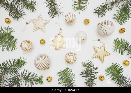 Komposition zu Weihnachten oder Neujahr. Tannenzweige und goldene Verzierungen auf weißem Hintergrund. Flach liegend, Draufsicht, Kopierbereich. Stockfoto