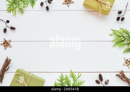 Weihnachts- oder Neujahrsarrangement. Rahmen aus Geschenkschachteln, Nadelholzzweigen und natürlichen Dekorationen auf weißem Holzhintergrund. Flach liegend, Draufsicht, Stockfoto