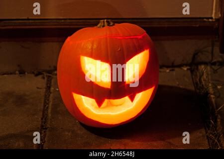Klassischer Kürbis für Halloween, der auf dem Boden steht und mit Teelichtern glänzt Stockfoto