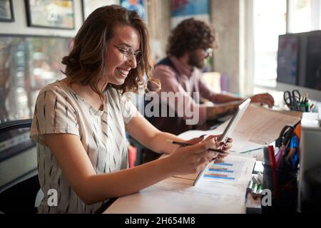 Junge Kollegen machen gemeinsam Schreibarbeiten im Büro Stockfoto