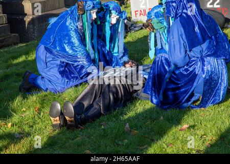 Die Rote Rebellenbrigade schließt sich der Blauen Rebellenbrigade auf dem Friedhof der Glasgow Necropolis zum Begräbnisfeier der COP26 an. Die weinenden Klimaaktivisten empfinden die COP26 als gescheitert und haben eine Scheinbegräbnis für den Gipfel abgehalten. Die COP26 wird zusammen mit allen vorherigen COP-Gipfeln in einem Grab ruhen. Stockfoto