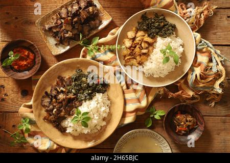 SE'i Sapi und SE'i Ayam. Geräuchertes Rind- und Hühnergericht von Nusa Tenggara Timur, serviert mit Reis und Cassava-Blättern Stockfoto