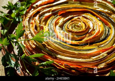 Gemüsekuchen mexikanische Sonne. Runde, offene Torte aus Zucchini, Auberginen und Karotten. Nahaufnahme von oben. Gesunde pflanzliche Lebensmittel. Vegetarismus. Spiralherb mit Auberginen. Stockfoto