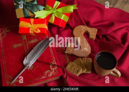 Das Buch von Sinterklaas, präsentiert einen Schokoladenbrief gewürzt Bisquit namens Speculaas und eine Tasse Kaffee. Konzept für den gemütlichen Abend Geschenke geben Stockfoto