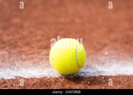 Tennisball auf weißer Linie auf dem Sandplatz aus nächster Nähe. Sportturnierwettbewerb, in- oder Out-Konzepte Stockfoto