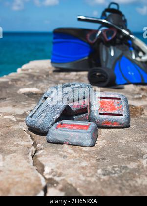 Sporttauchgewichte auf Felsen am Meer mit Schnorchelausrüstung im Hintergrund Stockfoto