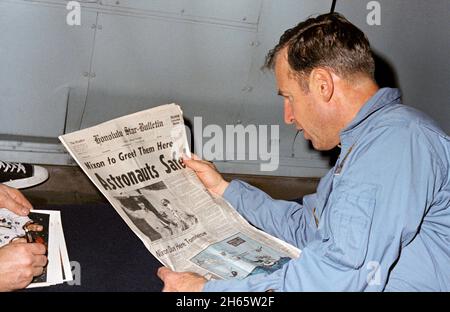 Astronaut James Lovell, Apollo 13-Missionskommandant, liest einen Zeitungsartikel über die sichere Wiederherstellung der von der Mission geplagten Aufgabe. Lovell ist an Bord der U.S.S. Iwo Jima, Prime Recovery Ship für Apollo 13, Stockfoto