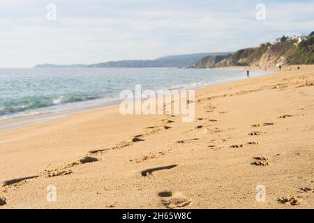 Fußabdrücke auf dem Sand am leeren Strand an sonnigen Tagen in Algarrobo, Chile. Not und Traurigkeit Konzepte Stockfoto