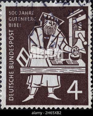 DEUTSCHLAND - UM 1954: Auf dieser in Deutschland gedruckten Briefmarke ist Johannes Gutenberg zu sehen, der die erste Bibel auf einer Druckmaschine druckt. Der Paost Stockfoto