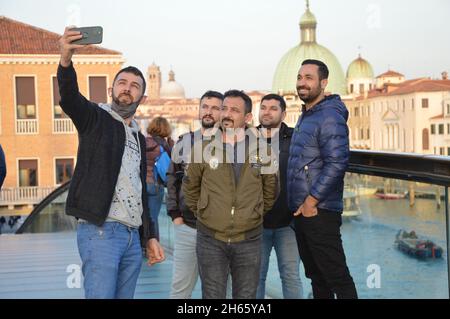 Männer aus dem Nahen Osten machen Selfie-Fotos mit dem Smartphone auf der Calatrava-Brücke des Canal Grande in Venedig, Italien - 11. November 2021. Stockfoto