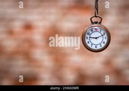 Taschenuhr gegen verwischte Ziegelwände. Zeitkonzept mit Kopierraum. Retro-Uhr. Selektiver Fokus Stockfoto