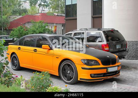 Kiew, Ukraine - 2. September 2017: BMW 7 Series Alpina in einem orangefarbenen matten Film vor dem Hintergrund anderer Autos und eines Hauses Stockfoto