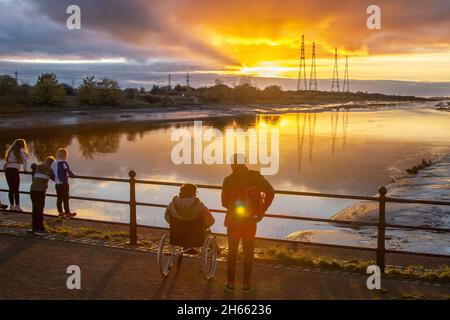 Sonnenuntergang am Flussufer in Preston, Lancashire. Wetter in Großbritannien. 13. November 2021. Ruhiger, sonniger Ausklang des Tages bei den Sonnenuntergängen über der Flussmündung des Ribble, aufgenommen von einem Ort, der bei Fotografen und Anglern gleichermaßen beliebt ist – der Bull Nose in den Preston Docks. Heute Abend beginnt trocken unter meist klarem Himmel. Mit einigen klaren Zaubersprüchen manchmal. Stellenweise bilden sich Nebelflecken und Nebel. Kredit; MediaWorlImages/AlamyLiveNews Stockfoto