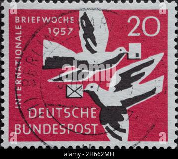 DEUTSCHLAND - UM 1957: Diese Briefmarke zeigt zwei weiße Brieftauben mit Briefen im Schnabel vor rotem Hintergrund. Text: International Let Stockfoto