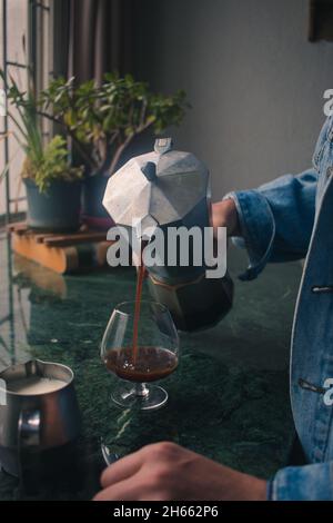 Modischer junger Mann, der Espresso aus der italienischen Espressomaschine gießt Stockfoto