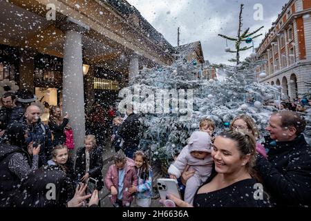 London, Großbritannien. November 2021. Jede Stunde wird auf der Covent Garden Piazza Kunstschnee überschüttet, was die festliche Atmosphäre der vorbeiziehenden Öffentlichkeit einbringt. Kredit: Guy Corbishley/Alamy Live Nachrichten Stockfoto