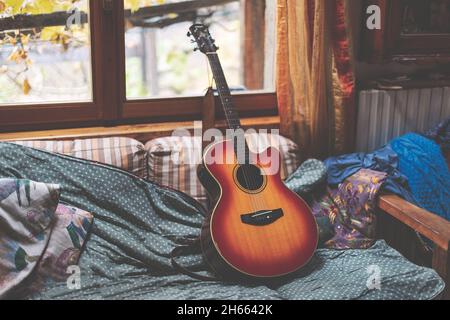 Akustische Gitarre, die nach dem Spielen auf einem Sofa ruht Stockfoto